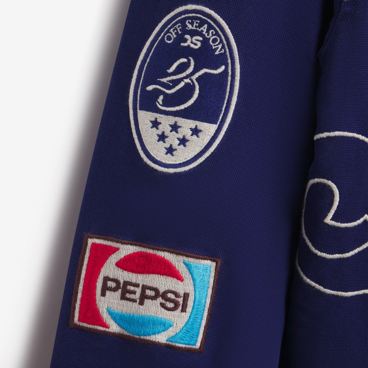 Detail of the Off Season crest and Pepsi flag embroidered patches on the sleeve